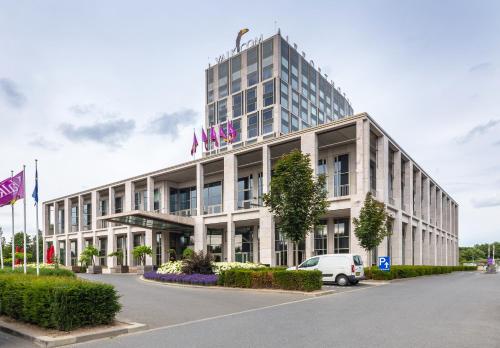 a building with a car parked in front of it at Van der Valk Airporthotel Düsseldorf in Düsseldorf