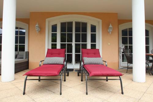 two chairs with red cushions sitting on a patio at Villa Wellness Homes in Mötz