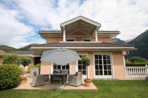 a house with a patio with an umbrella and chairs at Villa Wellness Homes in Mötz