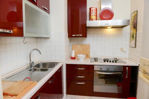 a small kitchen with red cabinets and a sink at Anagnina Home in Rome