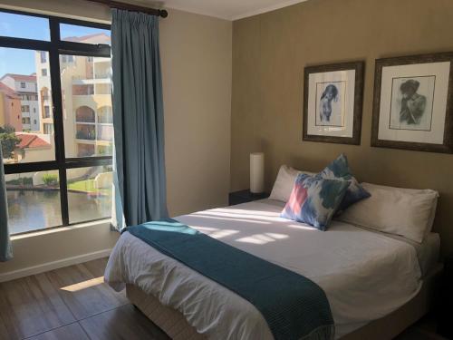 a bedroom with a bed and a large window at Island Club Portifino in Cape Town