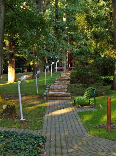 a stone path with a green bench in a park at Hotel Lövér Sopron in Sopron