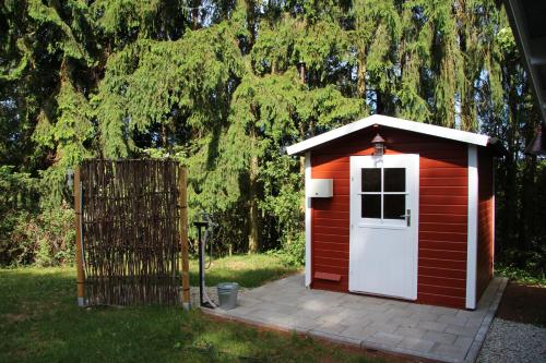 a red shed with a white door in a yard at Ferienwohnungen Alte Schule in Elchweiler