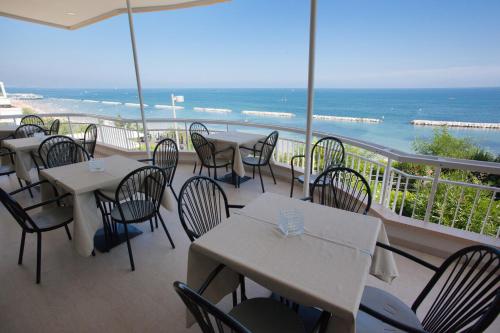 a restaurant with tables and chairs and the ocean at Hotel Adler in Gabicce Mare