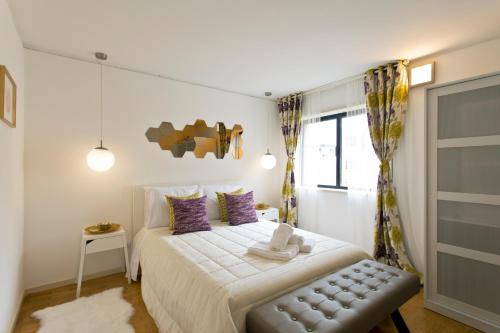 ein Schlafzimmer mit einem Bett mit lila Kissen und einem Fenster in der Unterkunft Amazing Comfy Flat with Balcony by Host Wise in Matosinhos