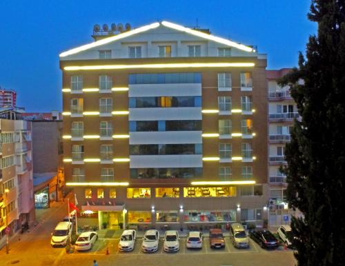 un grand bâtiment avec des voitures garées dans un parking dans l'établissement Efeler Hotel, à Aydın