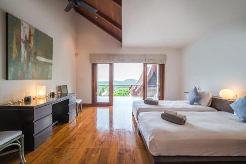 a bedroom with two beds and a desk and a window at Vichuda Hills in Layan Beach