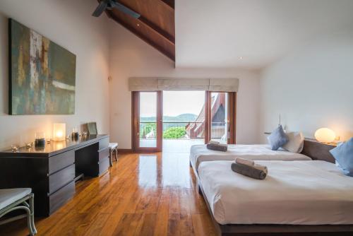 a bedroom with two beds and a desk and a window at Vichuda Hills by RESAVA in Layan Beach