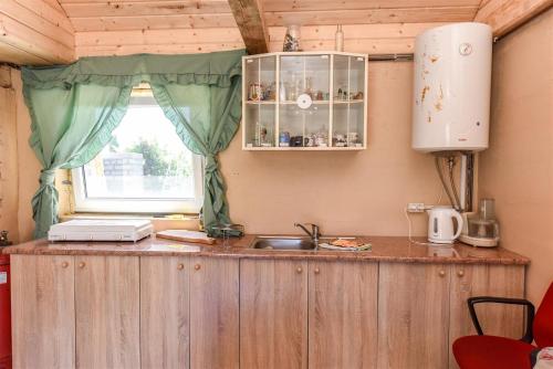 een keuken met een aanrecht met een wastafel en een raam bij Avoti in Jūrkalne