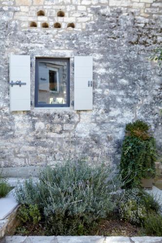 a window on a stone building with plants in front at Torri E Merli Boutique Hotel in Lákka