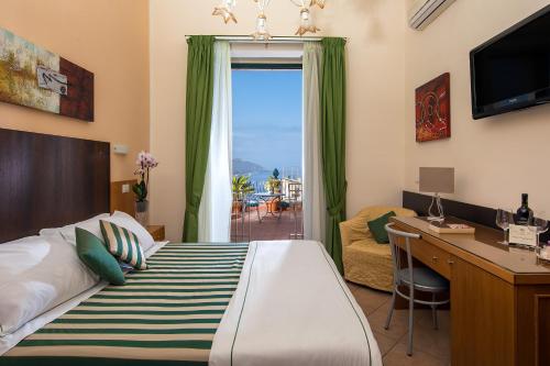 a bedroom with a bed and a desk and a window at Hotel "La Pensione Svizzera" in Taormina