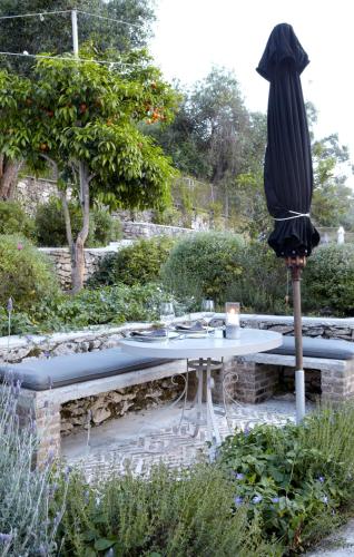 a table and an umbrella in a garden at Torri E Merli Boutique Hotel in Lákka