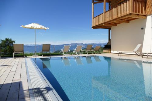 uma piscina com cadeiras e um guarda-sol em Hotel am Hang em Soprabolzano