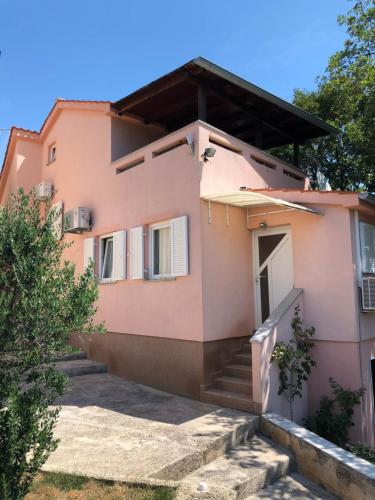 różowy dom ze schodami prowadzącymi do niego w obiekcie Villa Masha w mieście Omišalj