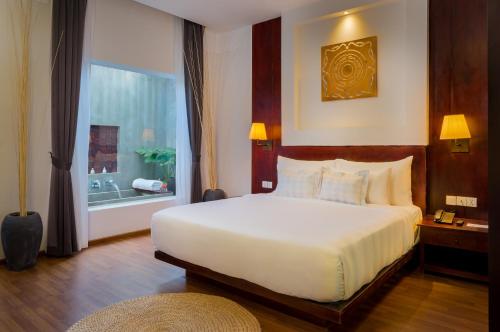 a bedroom with a large white bed and a window at Sabara Angkor Resort & Spa in Siem Reap