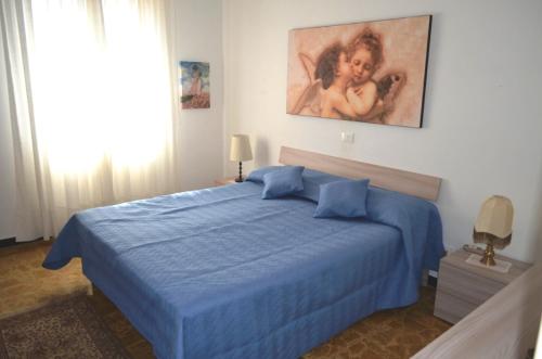 a bedroom with a blue bed and a painting on the wall at Casa Laura in Alassio