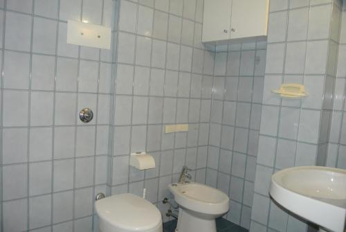 a white bathroom with a toilet and a sink at Appartamento SCHUBERT B in Lignano Sabbiadoro