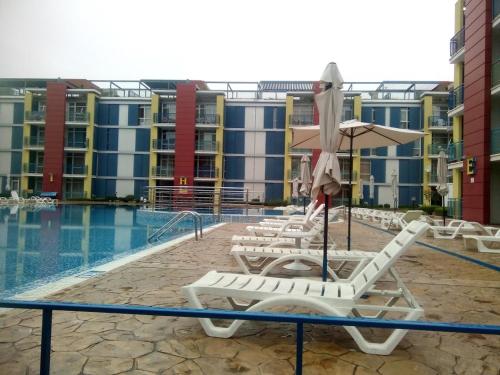 a group of chairs and an umbrella next to a pool at Studios in Complex Elit 4 in Sunny Beach
