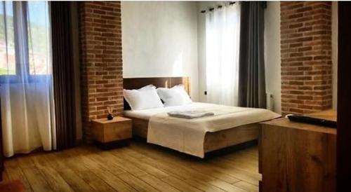 a bedroom with a bed and a brick wall at Vila Ilo in Tushemisht