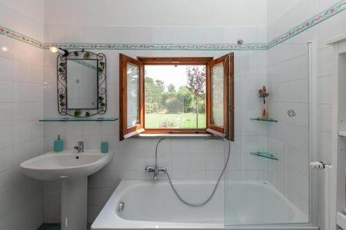 bagno con vasca, lavandino e finestra di La Casa in Toscana a Cortona