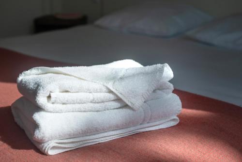 una pila de toallas blancas sentadas encima de una cama en l'AERODROME DE LA BAIE DE SOMME en Buigny-Saint-Maclou