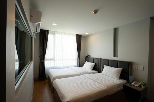 two beds in a room with a window at ONPA Hotel & Residence Bangsaen in Bangsaen