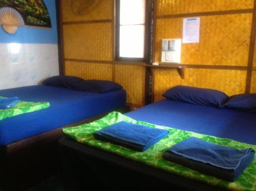 two beds in a room with blue sheets at New Hut Bungalow in Lamai
