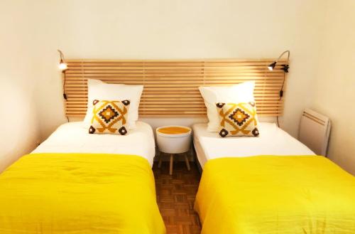 - 2 lits dans une petite chambre avec des draps jaunes dans l'établissement Le Solemar, à Cassis