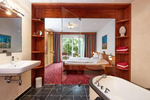 un bagno con vasca e una camera con letto di Hotel Hubertus a Brixen im Thale