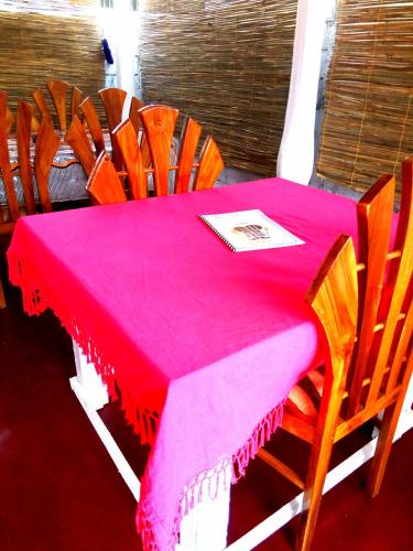 a table with a pink table cloth and wooden chairs at Gloriya Mathews in Negombo