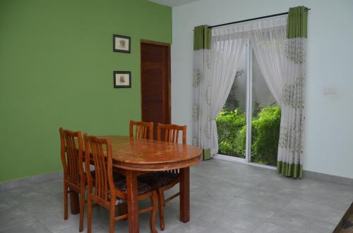 a dining room with a wooden table and chairs and a window at Kelaniya Heritage in Kelaniya