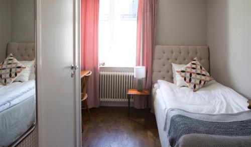 a small bedroom with two beds and a window at Hotell Blå Blom in Gustavsberg