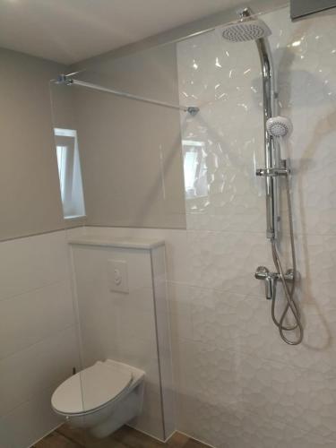 a white bathroom with a toilet and a shower at Apartment Skavo in Baška Voda