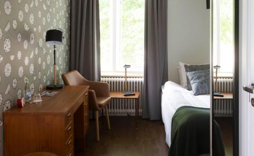 a bedroom with a desk and a bed and a window at Hotell Blå Blom in Gustavsberg