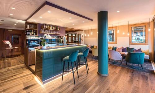 un bar in un ristorante con sgabelli blu di Marini's giardino Hotel a Tirolo