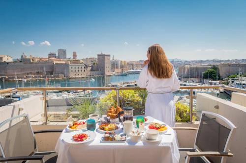 a woman standing on a balcony with a table of food at Sofitel Marseille Vieux-Port in Marseille