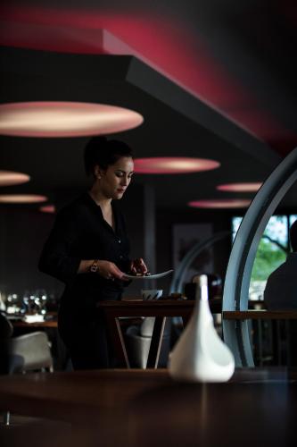 a woman standing at a counter in a restaurant at Logis Hôtel et Spa Chez Camillou in Aumont-Aubrac