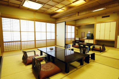 jadalnia ze stołami, krzesłami i oknami w obiekcie Hotel Fukiageso w mieście Kagoshima