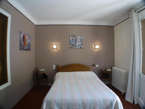 a bedroom with a bed and two lights on the wall at Hôtel Le Castelet in Ax-les-Thermes