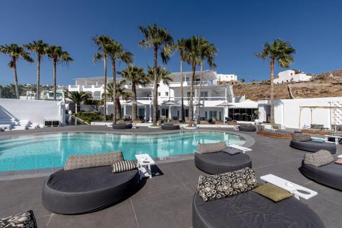 una piscina con tumbonas y sillas alrededor en Mykonos Blanc - Preferred Hotels & Resorts, en Ornos