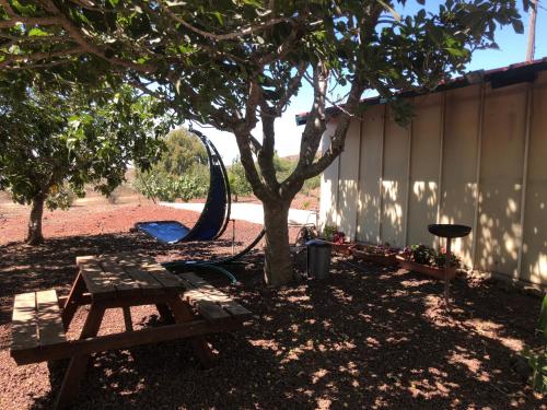 a picnic table and a playground next to a tree at Michal's Suites in Sha'al