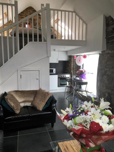 a living room with a couch and a staircase at The Barn at Pink Cottage in Crossgar