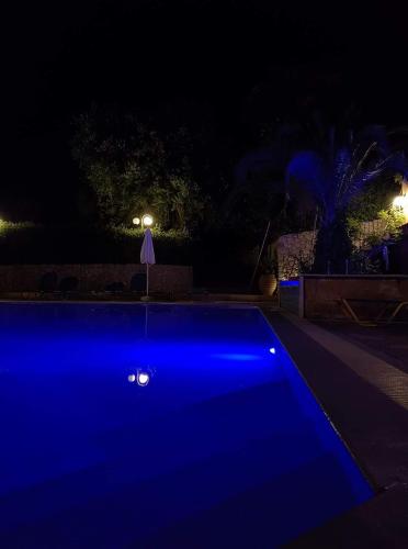 a swimming pool lit up in blue at night at Arianna in Paleokastritsa