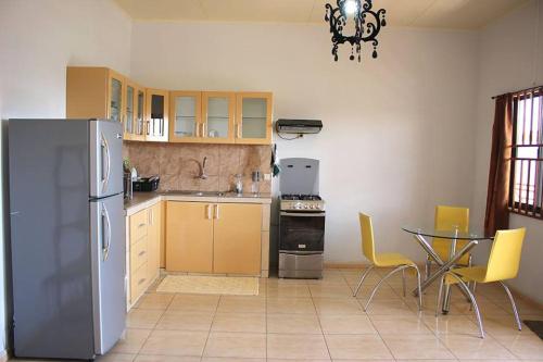 Rainville Apartments في باراماريبو: مطبخ مزود بثلاجة وطاولة وكراسي