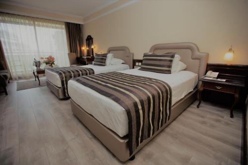 a hotel room with two beds and two lamps at Karaca Hotel in İzmir