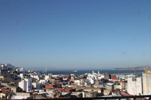 eine Stadt mit weißen Gebäuden und dem Meer im Hintergrund in der Unterkunft Riad Tingis in Tangier