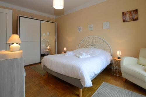 Un dormitorio con una cama blanca y una silla. en KAYSERSBERG city center - COTE VIGNOBLE -, en Kaysersberg