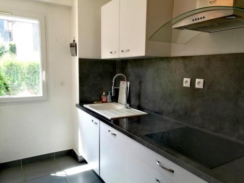 a kitchen with white cabinets and a sink at Grand appartement proche CHU in Rouen