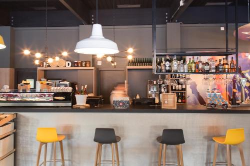 a bar with yellow stools in a restaurant at Ibis Madrid Fuenlabrada in Fuenlabrada