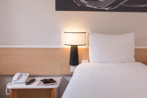 a bedroom with a bed and a lamp and a phone at Ibis Madrid Fuenlabrada in Fuenlabrada